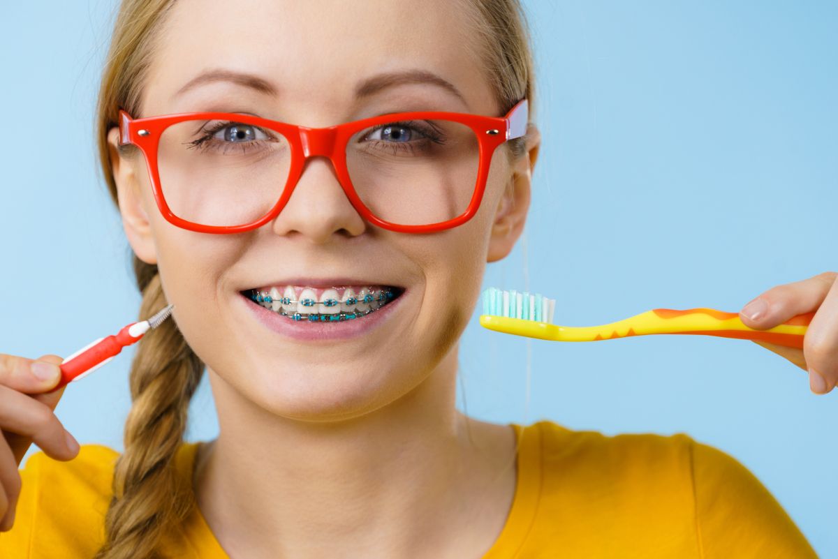 Young woman in red glasses smiling and showing her braces